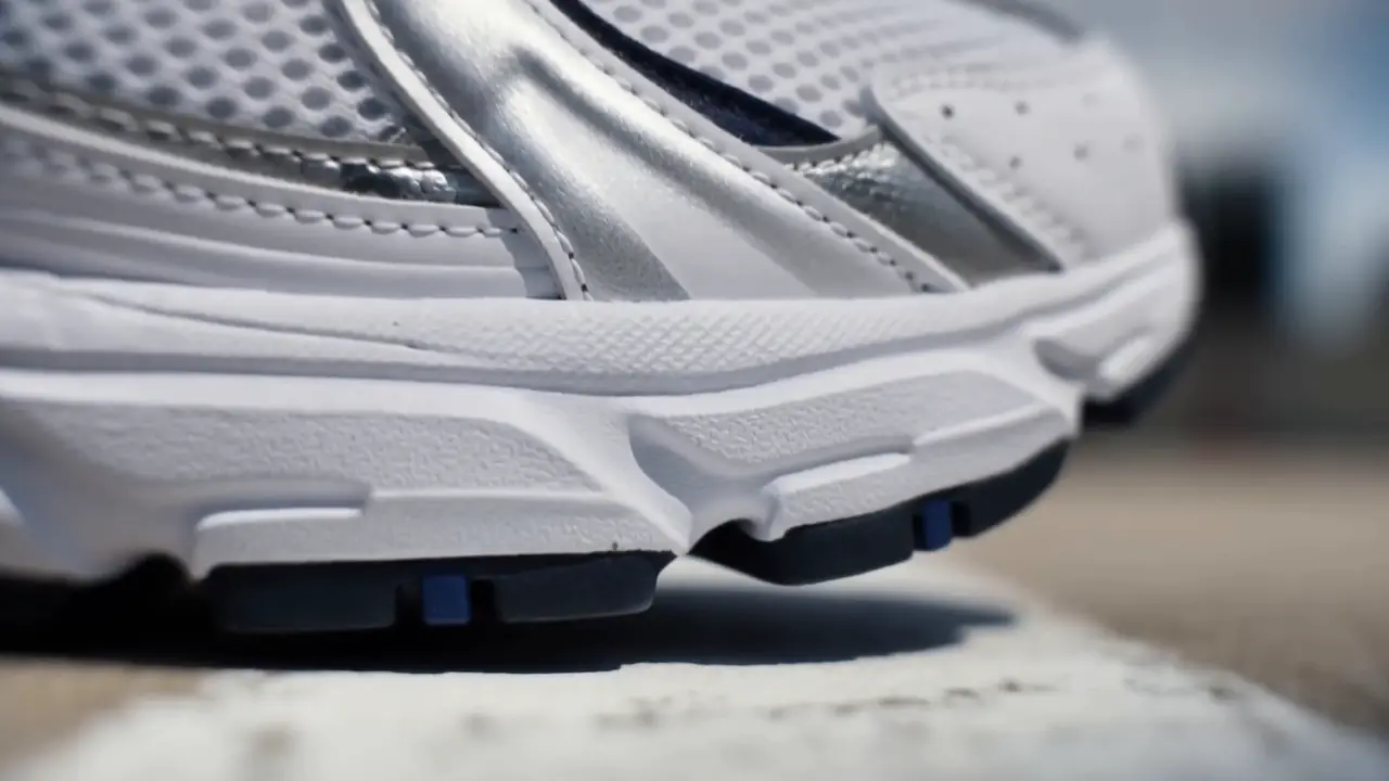 Close-up of a white and silver running shoe pressing into the track.
