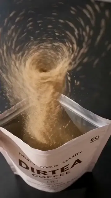 Coffee powder spirals up out of an open pouch.