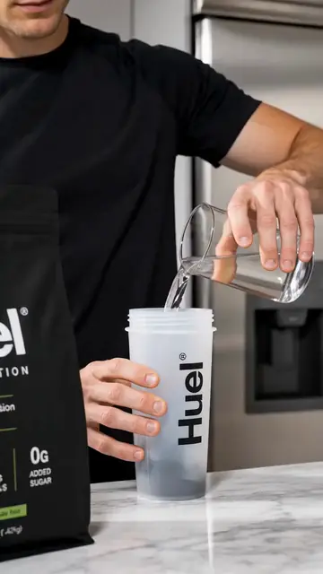 Water pours into a shaker on a kitchen counter.