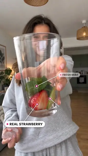 A glass of mint, lime and strawberry held up to the camera.