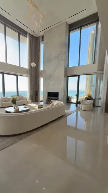 A penthouse living room with floor-to-ceiling windows over the sea.